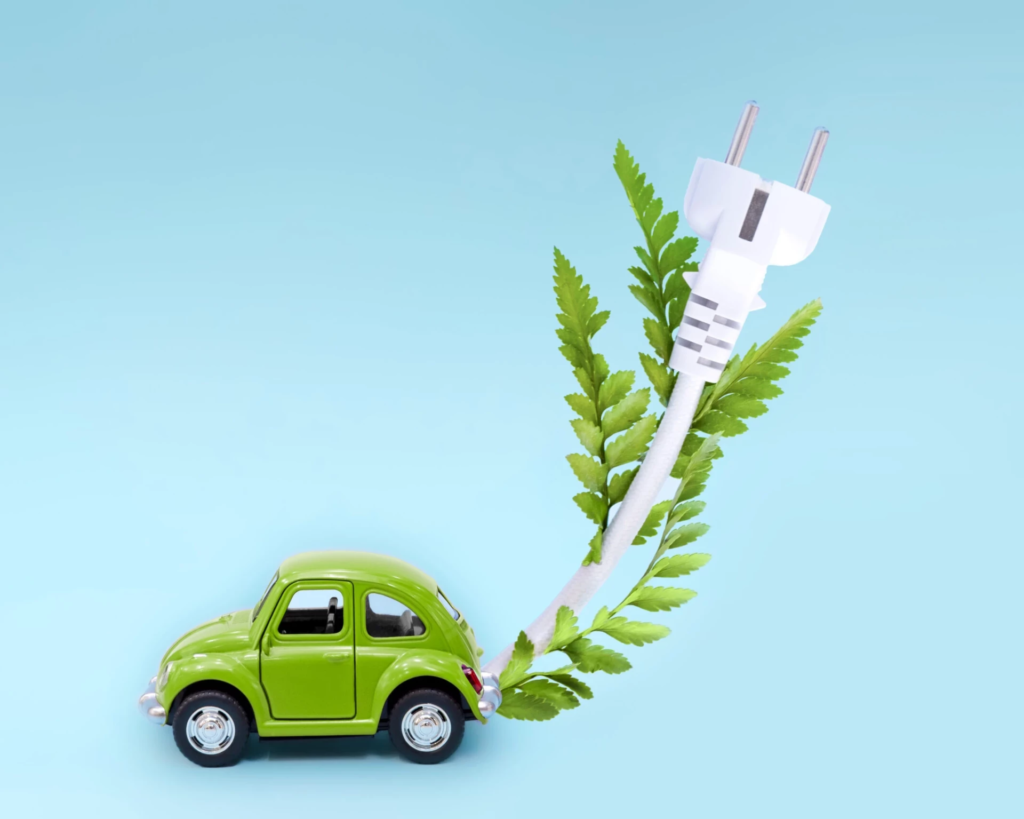 cropped-voiture-jouet-verte-comme-voiture-electrique-ev-cable-blanc-feuilles-vertes-bleu-scaled-1